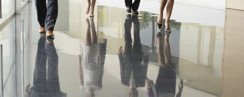 Low section of business people walking on marble flooring in office
